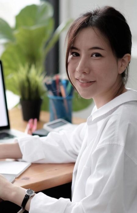 charming-asian-woman-working-at-the-office-using-a-laptop-looking-at-the-camera-free-photo (1)